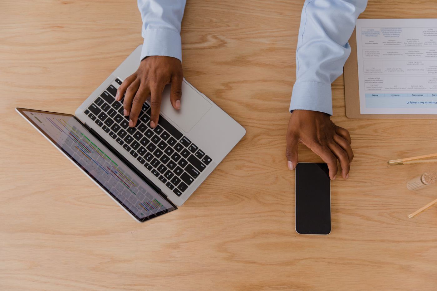 Mesa de trabajo con portátil, teléfono y documentos para preparar contenido